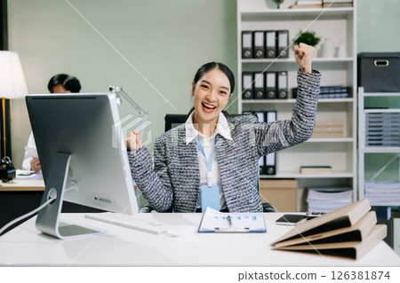 Young attractive Asian female office worker business suits smiling at camera with working 126381874