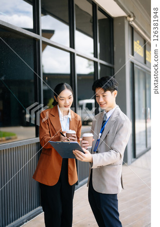 Businessman and woman going in city center in smart casual business style, talking, working together, stylish freelance people, holding coffee 126381948