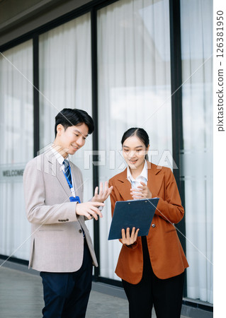 Businessman and woman going in city center in smart casual business style, talking, working together, stylish freelance people, holding coffee Businessman and woman going in city center in smart casual business style, talking, working together, stylish freelance people, holding coffee 126381950