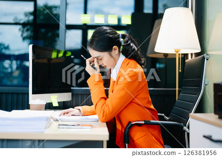 Asian woman feeling migraine head strain.Overworked businesswoman financier while working Asian woman feeling migraine head strain.Overworked businesswoman financier while working 126381956