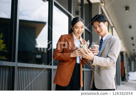 Businessman and woman going in city center in smart casual business style, talking, working together, stylish freelance people, holding coffee 126382054