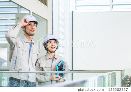 男工程師和女工程師站在室內，手裡拿著一台平板電腦 126382237