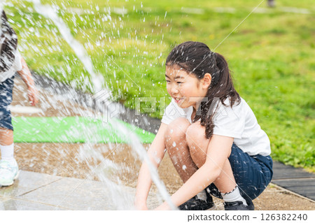 Girl playing in a fountain in the park 126382240