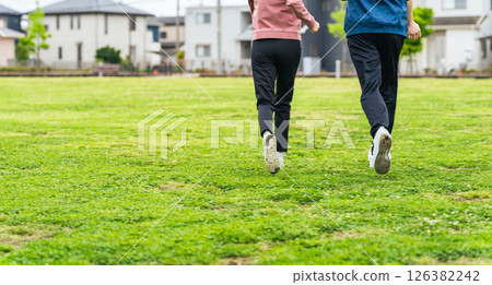 一對夫婦在公園草地上奔跑的背影 一對夫婦在公園草地上奔跑的背影 126382242