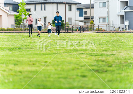 一家人在公園的草地上奔跑 一家人在公園的草地上奔跑 126382244