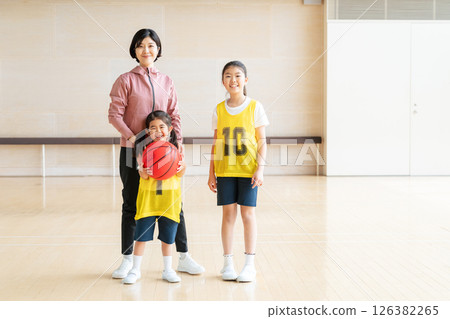 Children playing basketball and a female coach 126382265