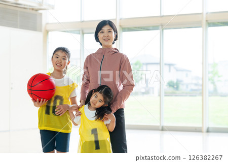 Children playing basketball and a female coach Children playing basketball and a female coach 126382267