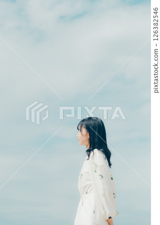 一位身穿白衣的女子站在安靜的海灘上 一位身穿白衣的女子站在安靜的海灘上 126382546