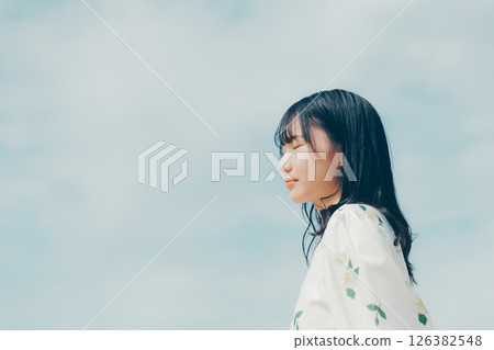 一位身穿白衣的女子站在安靜的海灘上 一位身穿白衣的女子站在安靜的海灘上 126382548