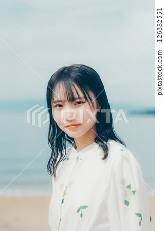 A woman in white standing on a quiet beach A woman in white standing on a quiet beach 126382551