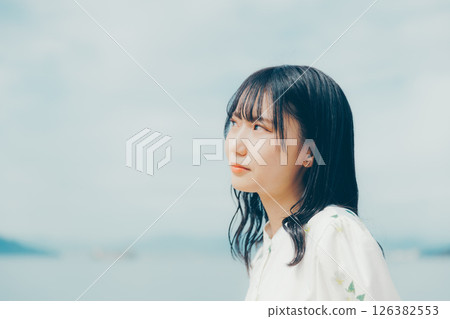 A woman in white standing on a quiet beach A woman in white standing on a quiet beach 126382553