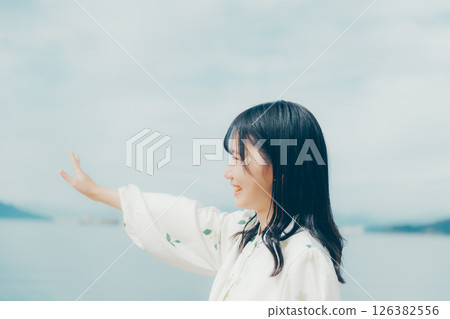 A woman in white standing on a quiet beach A woman in white standing on a quiet beach 126382556