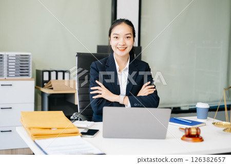 female lawyer celebrating success with documents at a desk, featuring a gavel, scales of justice, 126382657