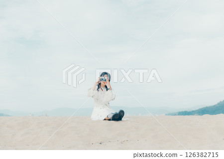 Girl holding a film camera on the beach Girl holding a film camera on the beach 126382715