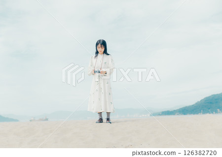 Girl holding a film camera on the beach Girl holding a film camera on the beach 126382720