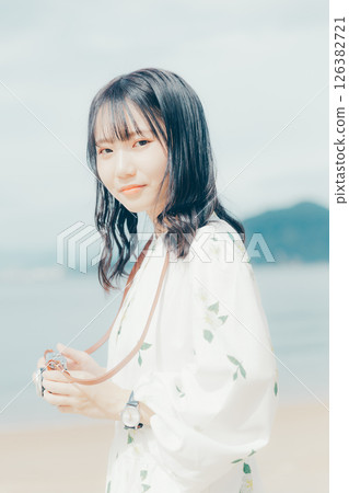 Girl holding a film camera on the beach 126382721