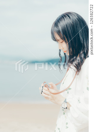 Girl holding a film camera on the beach Girl holding a film camera on the beach 126382722