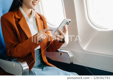 Asian executive excels in first class, multitasking with digital tablet, laptop. Travel in style, work with grace. 126382781