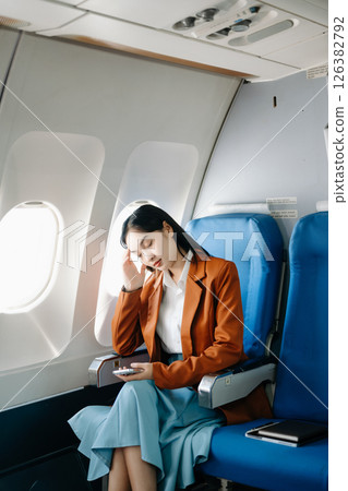 frustrated woman sitting on an airplane with her head in her hands. frustrated woman sitting on an airplane with her head in her hands. 126382792