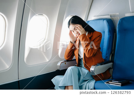 frustrated woman sitting on an airplane with her head in her hands. frustrated woman sitting on an airplane with her head in her hands. 126382793