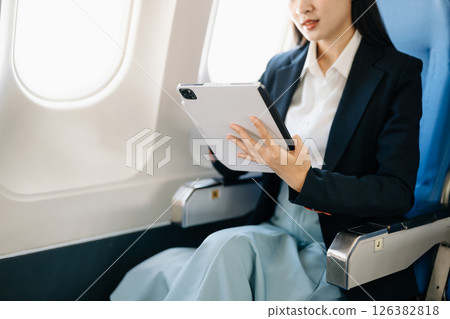 Asian executive excels in first class, multitasking with digital tablet, laptop. Travel in style, work with grace. 126382818