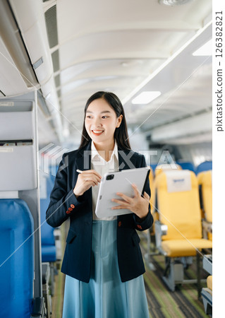 Asian executive excels in first class, multitasking with digital tablet, laptop. Travel in style, work with grace. 126382821