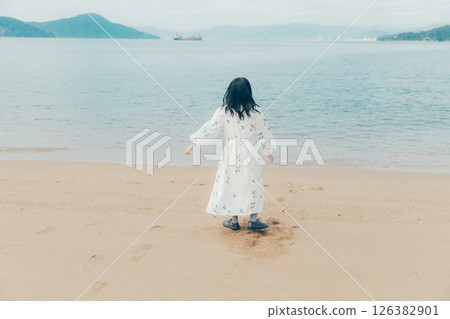 一位身著自然服裝的年輕女子站在海灘上 一位身著自然服裝的年輕女子站在海灘上 126382901