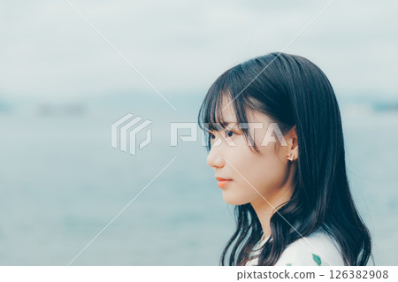 一位身著自然服裝的年輕女子站在海灘上 126382908