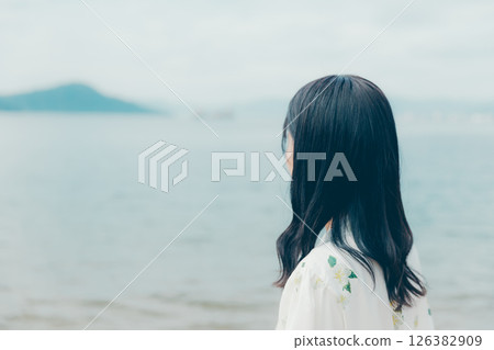 A young woman in natural clothing standing on the beach A young woman in natural clothing standing on the beach 126382909
