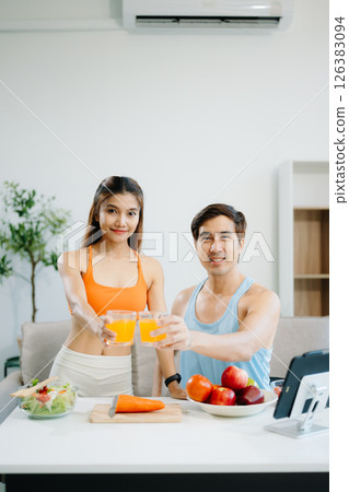 Fitness duo celebrating healthy living with fresh salad, fruits, and juice. A perfect balance of wellness, nutrition 126383094