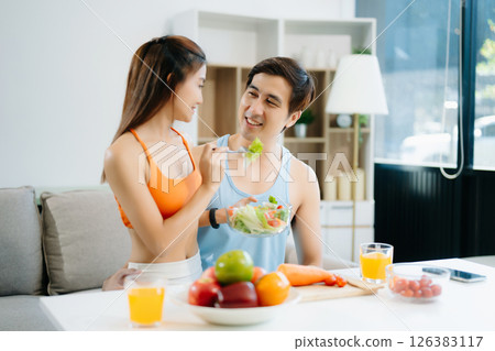 Fitness duo celebrating healthy living with fresh salad, fruits, and juice. A perfect balance of wellness, nutrition 126383117