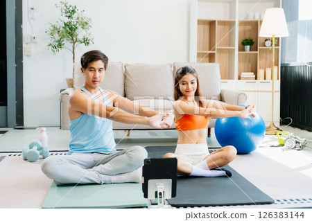 Fitness duo high fiving during an energetic workout session at home, featuring yoga mats, gym equipment 126383144