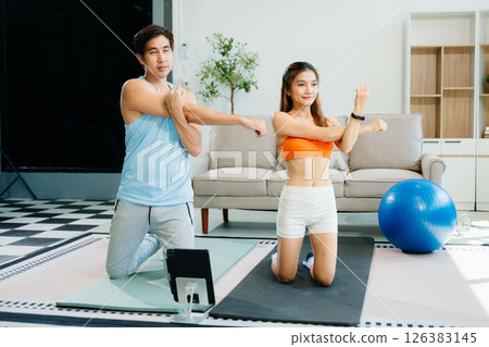 Fitness duo high fiving during an energetic workout session at home, featuring yoga mats, gym equipment Fitness duo high fiving during an energetic workout session at home, featuring yoga mats, gym equipment 126383145