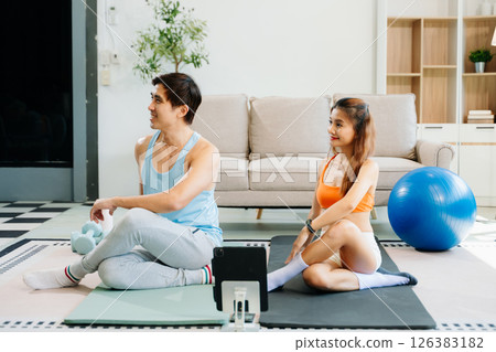 Fitness duo high fiving during an energetic workout session at home, featuring yoga mats, gym equipment Fitness duo high fiving during an energetic workout session at home, featuring yoga mats, gym equipment 126383182