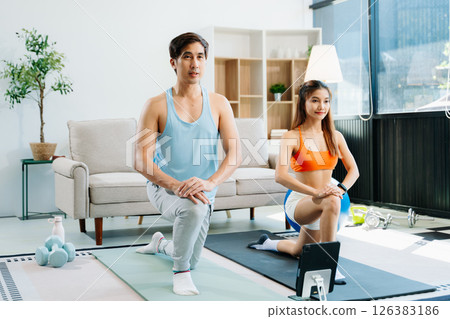 Fitness duo high fiving during an energetic workout session at home, featuring yoga mats, gym equipment Fitness duo high fiving during an energetic workout session at home, featuring yoga mats, gym equipment 126383186