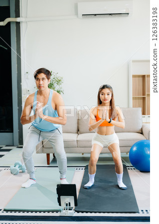 Fitness duo high fiving during an energetic workout session at home, featuring yoga mats, gym equipment Fitness duo high fiving during an energetic workout session at home, featuring yoga mats, gym equipment 126383198