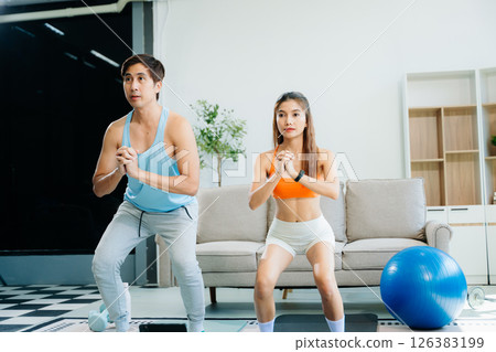 Fitness duo high fiving during an energetic workout session at home, featuring yoga mats, gym equipment Fitness duo high fiving during an energetic workout session at home, featuring yoga mats, gym equipment 126383199