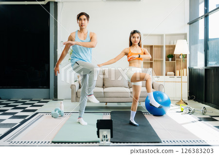 Fitness duo high fiving during an energetic workout session at home, featuring yoga mats, gym equipment Fitness duo high fiving during an energetic workout session at home, featuring yoga mats, gym equipment 126383203