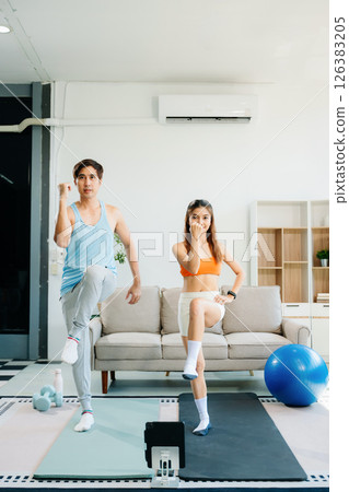 Fitness duo high fiving during an energetic workout session at home, featuring yoga mats, gym equipment Fitness duo high fiving during an energetic workout session at home, featuring yoga mats, gym equipment 126383205