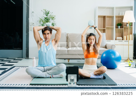 Fitness duo high fiving during an energetic workout session at home, featuring yoga mats, gym equipment 126383225
