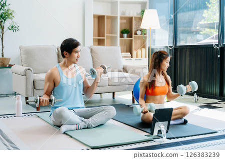 Fitness duo high fiving during an energetic workout session at home, featuring yoga mats, gym equipment Fitness duo high fiving during an energetic workout session at home, featuring yoga mats, gym equipment 126383239