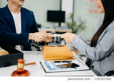 justice and law concept.passing bribe money in the envelop at lawyer office. justice and law concept.passing bribe money in the envelop at lawyer office. 126383360