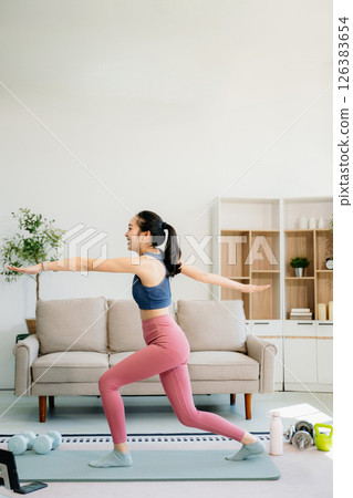 A young woman practices yoga and stretching with a mat and gym props, showcasing wellness, motivation, 126383654
