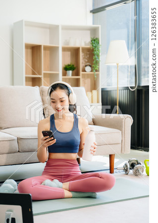 A young woman practices yoga and stretching with a mat and gym props, showcasing wellness, motivation, 126383655