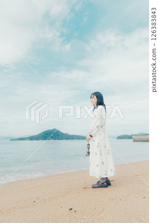 A calm sea and the back of a woman holding a lantern 126383843