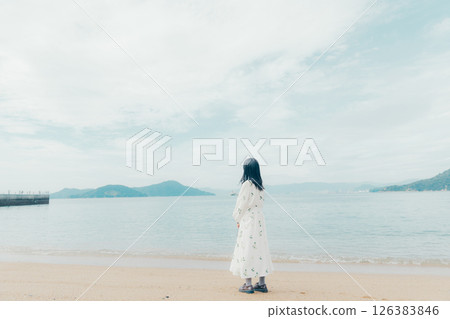A calm sea and the back of a woman holding a lantern 126383846