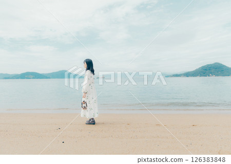 A calm sea and the back of a woman holding a lantern 126383848