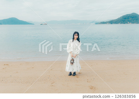 A calm sea and the back of a woman holding a lantern 126383856