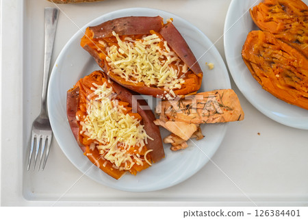 Savory baked sweet potatoes with melted cheese and grilled salmon on a sunny afternoon table 126384401