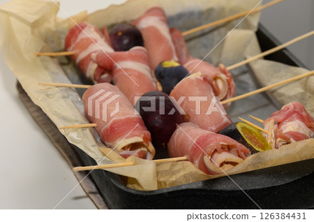 Savory rolls of prosciutto wrapped around fresh figs ready for an exquisite culinary experience 126384431